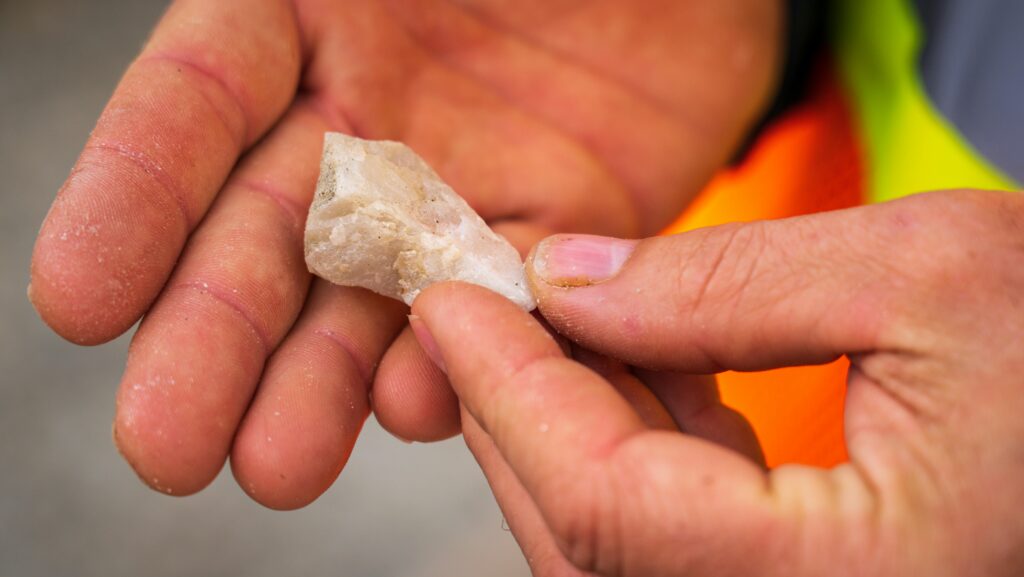 pexels-photo-17146230-17146230 Detailed close-up of hands examining a white mineral stone outdoors.