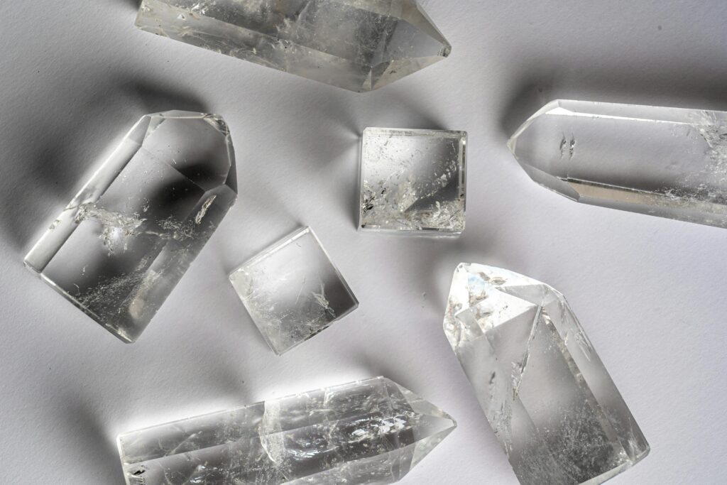 Clear quartz crystals arranged on a white surface, showcasing natural beauty and clarity.